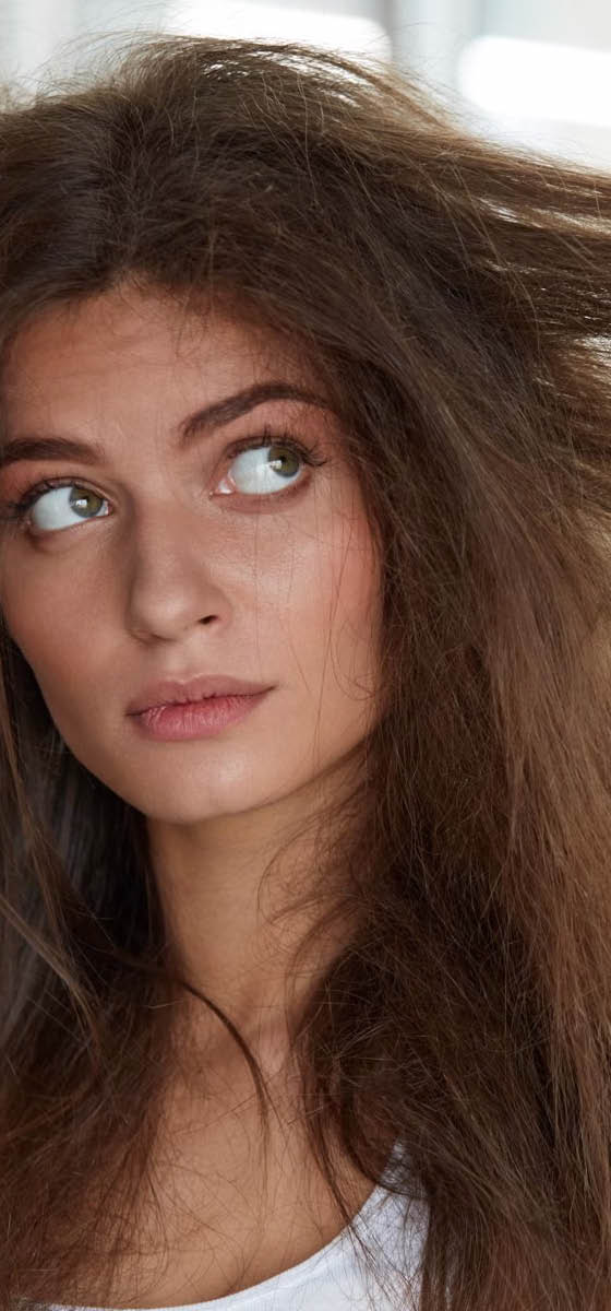 immagine di una ragazza con  capelli molto danneggiati. Si tira i capelli molto crespi a destra e sinistra
